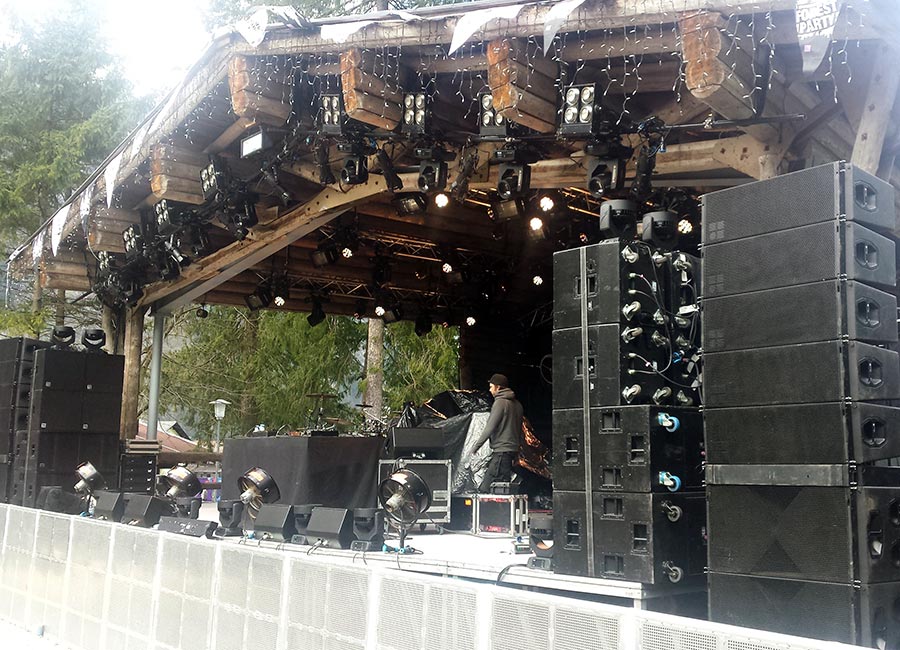 The Forest Stage at Snowbombing in Austria, with a timber roof, speaker stacks, trees and mountains behind